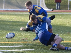 Dawson player loses the ball after he is tackled by Abbott  player during  men's rugby final Sunday at Memorial Field in Ste-Anne.