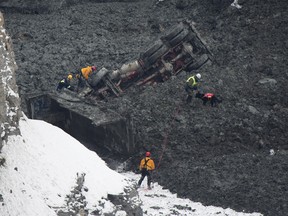 Rescuers search for missing workers in a quarry at L'Epiphanie, Que., Tuesday, January 29, 2013, following a landslide where a number of vehicles fell into the quarry. THE CANADIAN PRESS/Graham Hughes.