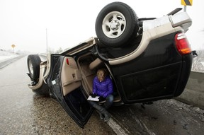A driver fills out a police report after rolling her vehicle on the onramp to I-80 in Salt Lake County Thursday, Jan. 24, 2013. An unusual freezing rain blanketed the Salt Lake City metropolitan area making driving around the valley extremely hazardous. The Salt Lake International Airport was closed down for several hours earlier today. (AP Photo/Deseret News, Jeffrey D. Allred)