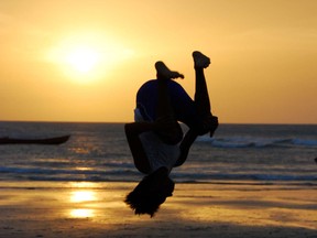 A teenager flips while practicing capoeira at dusk on the beach in Jericoacoara, in the state of Ceara in Brazil.