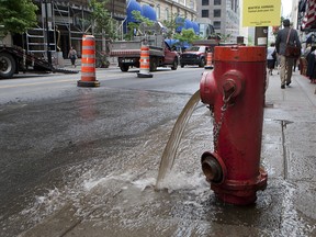 In this file picture from July of 2012, a fire hydrant is running on Peel street during a new round of underground-infrastructure repairs. According to testimony before the Charbonneau inquiry, Montreal taxpayers' money flowed just as easily and did so for decades, as a lack of oversight at city hall saw infrastructure costs soar up to 85 per cent more than for similar work in other municipalities. (Marie-France Coallier/THE GAZETTE)