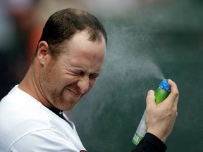 Baltimore Orioles left fielder Lew Ford sprays sunscreen on his face before a baseball spring training exhibition game against the New York Yankees, Monday, Feb. 25, 2013, in Sarasota, Fla. (AP Photo/Charlie Neibergall) ORG XMIT: FLCN112