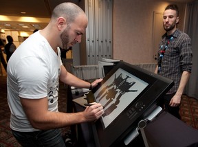 Artist Joel Viegas draws a video game character at the Wacom booth during last year's Montreal International Games Summit. Wacom rep Jerome Abramovitch is pictured at right.(Allen McInnis/THE GAZETTE)