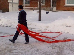 A police officer takes down police tape outside house in Dorval on Jan.22, 2013.