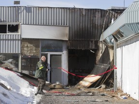 Surété du Québec officer investigates fire which gutted custom furniture business on Grand Blvd. in Île Perrot early Wednesday morning.