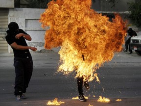 A Bahraini anti-government protester is engulfed in flames when a shot fired by riot police hit the petrol bomb in his hand that he was preparing to throw during clashes in Sanabis, Bahrain, Thursday, March 14, 2013. Protests and clashes erupted in opposition areas nationwide Thursday with government opponents observing a "Dignity Strike" blocking roads, closing shops, protesting and staying home from work and school called by the more radical February 14 youth group.