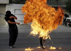 A Bahraini anti-government protester is engulfed in flames when a shot fired by riot police hit the petrol bomb in his hand that he was preparing to throw during clashes in Sanabis, Bahrain, Thursday, March 14, 2013. Protests and clashes erupted in opposition areas nationwide Thursday with government opponents observing a "Dignity Strike" blocking roads, closing shops, protesting and staying home from work and school called by the more radical February 14 youth group.