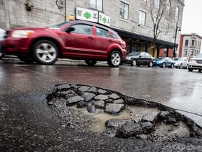 Cars drive past a large pothole on St. Laurent Blvd. near the corner of Sherbrooke St. As Montreal streets begin their annual, springtime  deterioration, a deadlock at city hall has left the city with no asphalt for repairs. (Dario Ayala / THE GAZETTE)