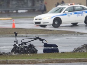 A Montreal police robot approaches a suspicious package at the Esso gas station at Fairview on Tuesday afternoon.