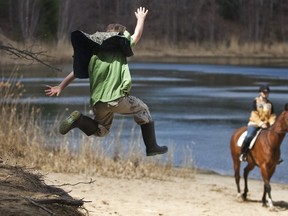 Kerrsen Bridges-Parkinson, 7, jumps from a small sand dune as Cassie Lawson, 16, on her horse Champ, watches during a walk organized by the organization Friends of Dunes Lake in 2010 to protest the development of homes near Dunes Lake.