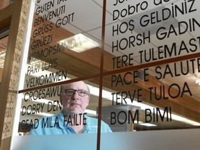 Harry Schick, the owner of  Swiss Vienna Pastry and Delicatessen at Plaza Pointe Claire, April 25, 2013, peers through a multilingual commercial sign  that has got him into trouble with Quebec's language police.