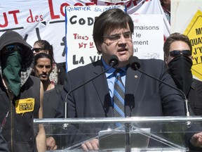 Two masked demonstrators stand behind Liberal MP Denis Coderre yesterday as he announces his intention to run as Montreal city mayor. That incident, as well as some rough radio interviews today, have made Coderre's first week as a mayoral candidate a rough one.  THE CANADIAN PRESS/Paul Chiasson