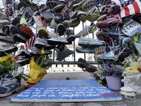 Running shoes hang on a fence at a makeshift memorial near the Boston Marathon finish line in Boston's Copley Square Thursday, April 25, 2013 in remembrance of the Boston Marathon bombings. The Boston bombings on April 15 and the arrest in Canada a week later of two men allegedly plotting to derail a Via Rail train refocused Canadians' attention on terrorism. (AP Photo/Elise Amendola)