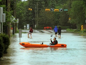 A Calgarian paddled a boat along a street in the Elbow Park area of Calgary after the Elbow River spilled over the banks and flooded a large area surrounding it on Friday. Prime Minister Stephen Harper was on his way to southern Alberta on Friday to tour areas devastated by flooding that has displaced tens of thousands of people.
(Colleen De Neve/Calgary Herald)