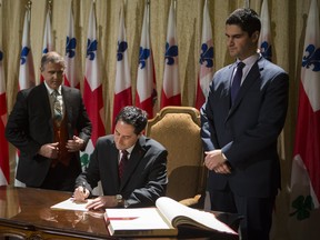 In this file photo from November of last year, council speaker Harout Chitilian, right, looks on as newly elected interim mayor Michael Applebaum, centre, signs in as replacement for former mayor Gerald Tremblay. Now that Applebaum has resigned, Chitilian is perceived as the front runner among the candidates to replace him in a vote by council that will be overseen by city clerk  Yves Saindon, left. (Dario Ayala/THE GAZETTE)