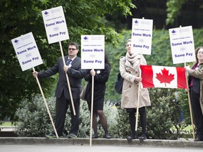 Several people were on hand to protest cuts to Canada's diplomatic corps outside the Palace of Westminster before Canadian Prime Minister Stephen Harper spoke to members of the British Parliament in the Queen's robing room in the Palace of Westminster, London on Thursday, June 13, 2013. THE CANADIAN PRESS/Adrian Wyld