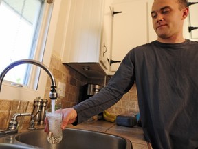 Jarrod White pours water into a drinking glass at his home in Domaine-en-Haut, an area of Vaudreuil that has been under a boil water advisory for seven years.