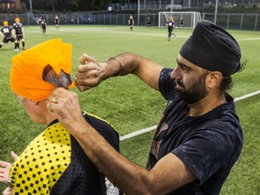 Sonics player Talwinderpal Singh, right, has sat out three games in the Pointe Claire Soccer League because he wears a patka. Singh helps Meilan Carr, goalie for the Selects with a bandana in a display of support at Terra Cotta Park in Pointe Claire, on Friday, June 14.
