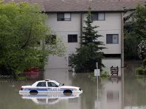 A police car sits stuck in a parking lot of an apartment building after heavy rains have caused flooding, closed roads, and forced evacuation in Calgary, Alta., Friday, June 21, 2013. THE CANADIAN PRESS/Jeff McIntosh