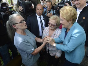 Quebec Premier Pauline Marois (right) holds hands with resident Francoise Roy as Lac-Megantic, Que. mayor Colette Roy-Laroche looks on, as they make their way to a news conference in Lac-Megantic, Que. on Thursday July 11, 2013. THE CANADIAN PRESS/Ryan Remiorz