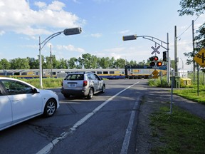 Cars wait for a west bound Via Rail train to pass at the Terrasse-Vaudreuil level crossing.