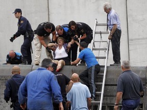 In this photo taken on Wednesday July 24 2013, a woman is evacuated from a train car at the site of a train accident in Santiago de Compostela, Spain. Spanish police on Friday detained the driver of a train that crashed in northwestern Spain, lowered the death toll from 80 to 78 and took possession of the "black box" of the train expected to shed light on why it was going faster than the speed limit on the curve where it derailed. And in an interview with The Associated Press, an American passenger injured on the train said he saw on a TV monitor screen inside his car that the train was traveling 194 kph (121 mph) seconds before the crash — far above the 80 kph (50 mph) speed limit on the curve where it derailed. (AP Photo/La Voz de Galicia/Xoan A. Soler)