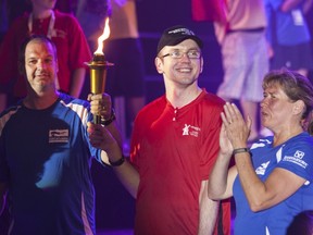 Torch bearer Stephan Quick stands in the Bob Birnie arena with Sergeant Marc Ratte and Constable Mary Jack  of the Montreal police.