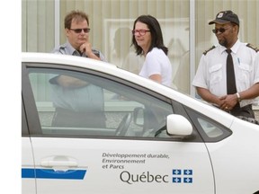 An Environment Quebec employee, centre, speaks with security officials outside Reliance Power offices on Thursday.