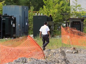 A security guard walks past electrical transformers stored in the yard at Reliance Power Equipment in Pointe Claire.  The yard was the site of a PCB spill Reliance has now agreed to clean up.     (John Mahoney/THE GAZETTE)