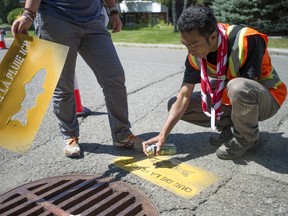 Moot scout member Abdul Azis of Indonesia paints a yellow fish next to storm drains as part of the Yellow Fish Road intiative in Pierrefonds- Roxboro.
