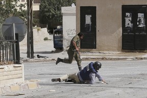 AFP reporter Sammy Ketz, hits the ground as a Syrian soldier runs past during sniper fire in the ancient Christian Syrian town of Maalula, on September 18, 2013, scene of recent fighting between pro-government troops and rebel forces. Ketz and a photographer were reporting on the town which lies around 55 kilometres (34 miles) from Damascus and which is strategically important for rebels, who are trying to tighten their grip on Damascus. (Anwar Amro / AFP-GETTY IMAGES)