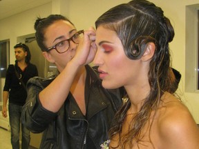 A hair artist puts the finishing touches on a model's hair before she hits the runway.