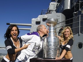 Los Angeles Kings Ice Crew members Arsee, left, and Jessica pose with fan Marc Volpe, center, as he kisses the Stanley Cup on tour at the USS Iowa in Los Angeles, Wednesday, Jan. 16, 2013. Hockey's top prize was presented to the Kings, who defeated the New Jersey Devils four games to two in the NHL hockey Stanley Cup finals last June. (AP Photo/Damian Dovarganes)