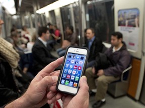 A commuter looks at his smart phone on the Metro Wednesday, September 25, 2013 in Montreal. Telus Rogers and Quebecor have announced plans to build a wireless network in the subway that will allow riders to use their phone, laptops and tablets undergroundTHE CANADIAN PRESS/Ryan Remiorz