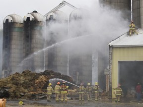 Firefighters dose the smouldering piles of hay.