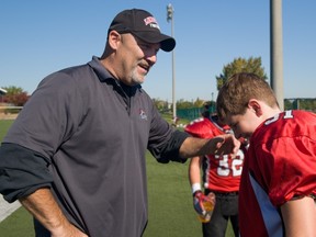 Lakeshore Cougars football coach Jim States offer words of encouragement to player Jack Artzy of during a game.