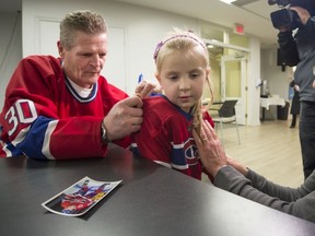 Nilan signs his name to the hockey shirt of 5-year-old Emily Dillon as her father, Tom Dillon, looks on during a visit by Nilan to Le Cambridge.