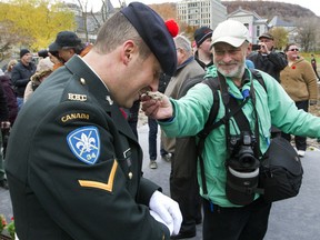 Robin Edgar, right, wipes the runny nose of a Canadian soldier who was standing on sentry duty at the annual Remembrance Day ceremony at McGill University in downtown Montreal, Thursday November 11, 2013.  The annual event is organized by the Royal Canadian Legion and ceremonies are held across the country.