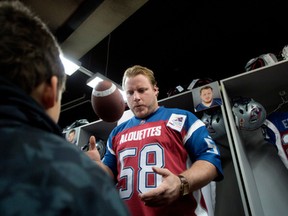 Luc Brodeur-Jourdain tosses a football to 7 year old Mathias M Bernier as season ticket holders visit the Montreal Alouettes' locker room in Montreal on Sunday December 1, 2013.