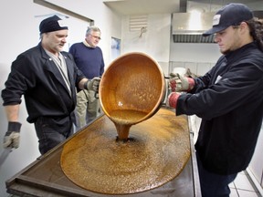 John Angus, rear, watches as Lorne Jenkins, left, and his nephew  Jeff Jenkins pour boiling raw candy to cool at Stilwells in Lasalle on Monday December 2, 2013.