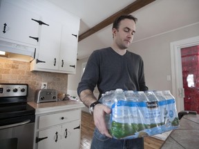 MONTREAL, QC: JANUARY 25, 2014 -- Jarrod White carries water bottles, which he must buy in order to get fresh water, at his home in Vaudreuil on January 25, 2014. (Robert Amyot / THE GAZETTE)