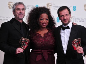 Mexican filmmaker Alfonso Cuaron (L) and British producer David Heyman (R)  flank presenter Oprah Winfrey (C) with their awards for an Outstanding British Film for Gravity at the BAFTA British Academy Film Awards at the Royal Opera House in London on February 16, 2014. (CARL COURT/AFP/Getty Images)
