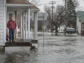 Michel Lefebvre watches as snow melt from the fields around St-Clet floods streets in the town on Tuesday, April 8, 2014.