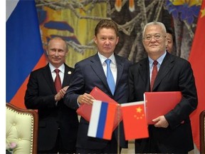 Russia's President Vladimir Putin, left, applauds, during signing ceremony in Shanghai, China on Wednesday, May 21, 2014 while Russian Gazprom CEO Alexei Miller, second left, and China's CNPC head Zhou Jiping, second right, hold documents, China's President Xi Jinping, stands partially seen at right. China signed a long-awaited, 30-year deal Wednesday to buy Russian natural gas worth some $400 billion.
