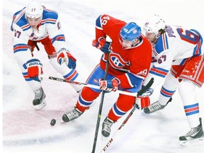 Canadiens’ Michael Bournaval, centre, competes for the puck with New York Rangers John Moore, left and Benoît Pouliot during National Hockey League game in Montreal Saturday November 16, 2013.
