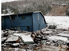 A cottage sits half submerged in lake water after a mudslide on the other side of the lake caused a wave of water and ice that pulled it off the footing and in to Lac-des-Seize-Îles  north of Montreal on Tuesday April 15, 2014.