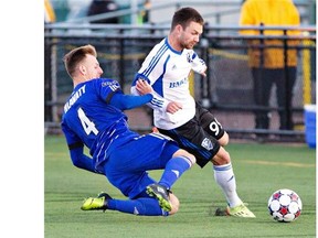 Impact’s Jack McInerney is tackled by Edmonton FC’s Neil Hlavaty during second-half action of the Amway Canadian Championship semifinal in Edmonton on Wednesday.