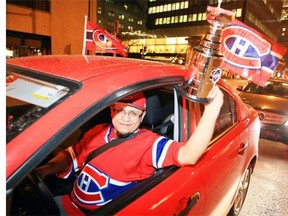 Jeremy Sandoval holds a miniature Stanley Cup out of his window as he drives down René-Lévesque Blvd. as Canadiens fans celebrate in the streets after Habs Stanley Cup series victory over the Bruins in Boston, in Montreal Wednesday May 14, 2014.