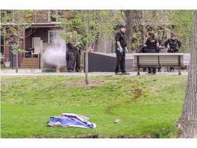 Montreal police investigators look for clues on Friday, May 16, 2014 after a man’s body was found at Monk Park in Lachine. A blue tarp and drag marks remain at the scene.