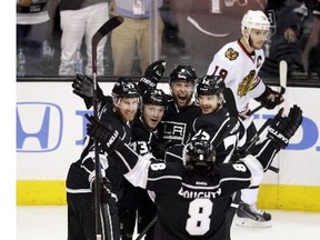 Los Angeles Kings' Jeff Carter (77), Tyler Toffoli (73), Jake Muzzin (6), Dustin Brown (23) and Drew Doughty (8) celebrate a goal by Muzzin as Chicago Blackhawks' Jonathan Toews (19) skates behind them during the first period of Game 4 of the Western Conference finals of the NHL hockey Stanley Cup playoffs on Monday, May 26, 2014, in Los Angeles.